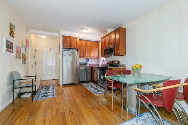 108-27 63rd Ave Unit 4B, Forest Hills, NY 11375 - kitchen with appliances with stainless steel finishes, light wood-style flooring, brown cabinetry, and baseboards