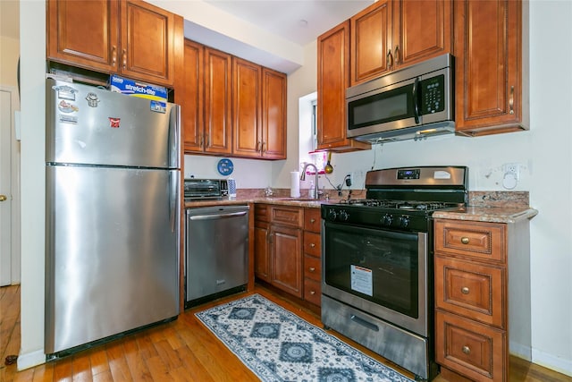 108-27 63rd Ave Unit 4B, Forest Hills, NY 11375 - kitchen featuring stainless steel appliances, light wood-style floors, brown cabinets, and a sink
