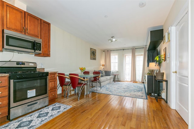 108-27 63rd Ave Unit 4B, Forest Hills, NY 11375 - kitchen featuring stainless steel appliances, light wood finished floors, brown cabinets, open floor plan, and light countertops