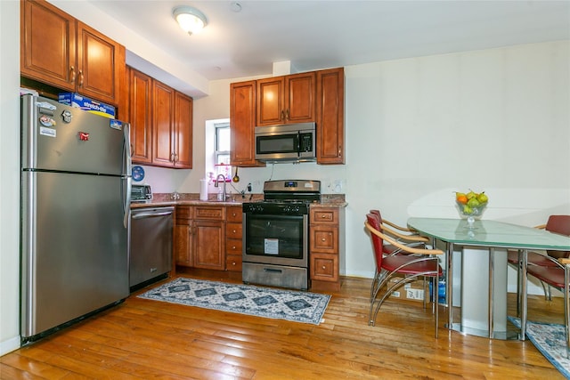 108-27 63rd Ave Unit 4B, Forest Hills, NY 11375 - kitchen featuring stainless steel appliances, light wood finished floors, a sink, and brown cabinets