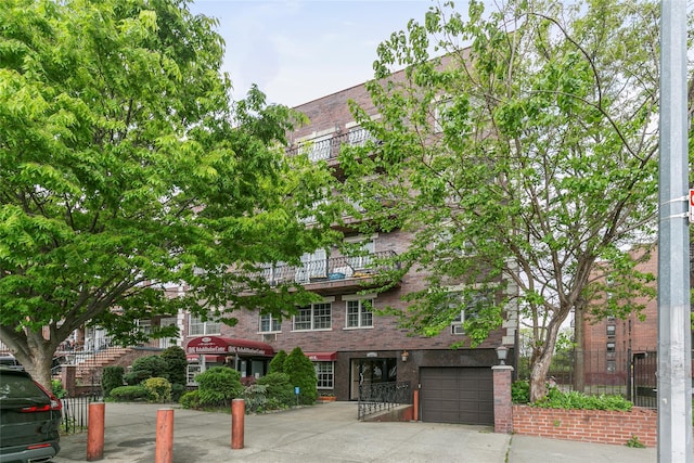 108-27 63rd Ave Unit 4B, Forest Hills, NY 11375 - view of front facade with a garage, brick siding, and concrete driveway