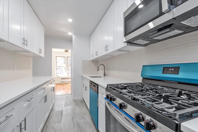 kitchen featuring a sink, light countertops, stainless steel appliances, white cabinetry, and backsplash