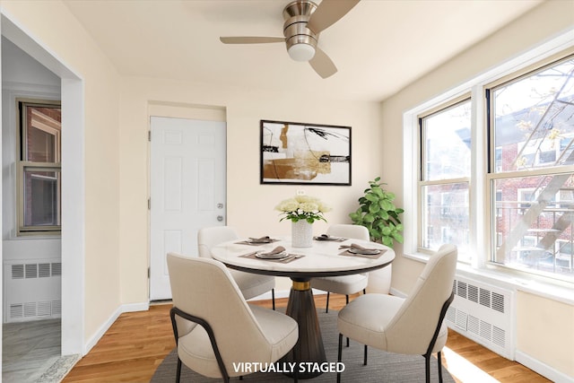 dining room featuring radiator heating unit, baseboards, light wood-style floors, and a wealth of natural light