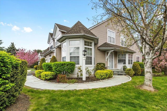 view of front of home with a shingled roof and a front lawn