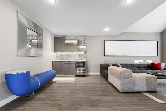 interior space featuring wine cooler, wood finished floors, baseboards, recessed lighting, and a bar