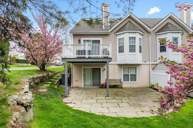 back of property featuring stucco siding, a chimney, central air condition unit, a patio, and a yard
