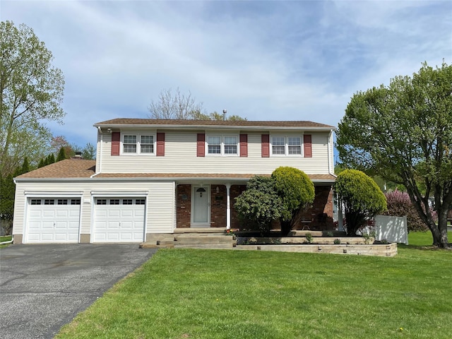 traditional home with an attached garage, aphalt driveway, a front yard, and a porch