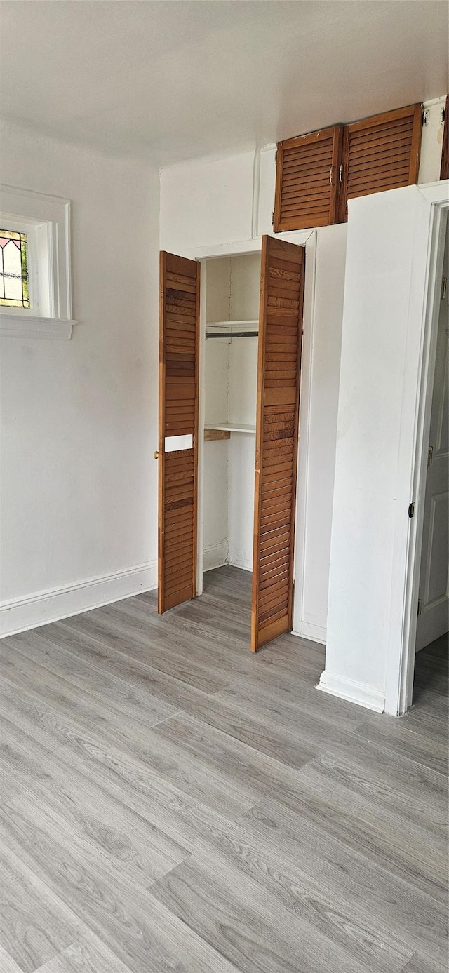 unfurnished bedroom with baseboards, a closet, and light wood finished floors