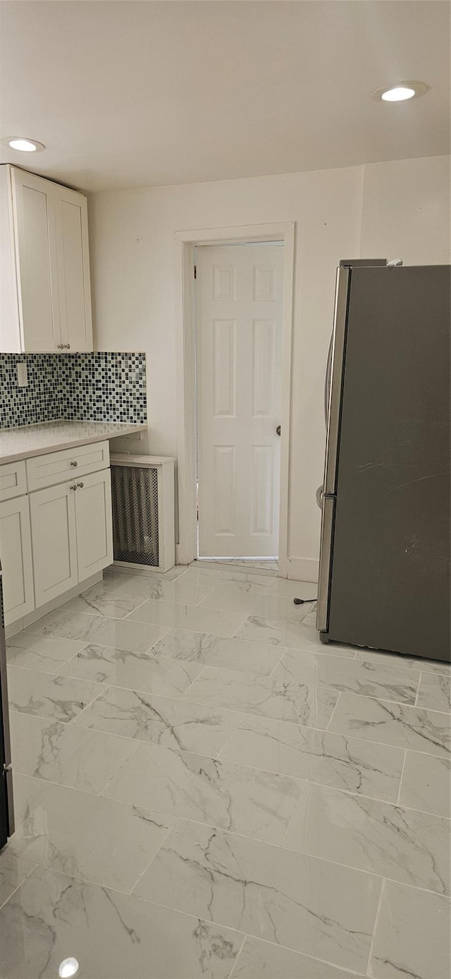 kitchen with freestanding refrigerator, recessed lighting, light countertops, white cabinets, and backsplash