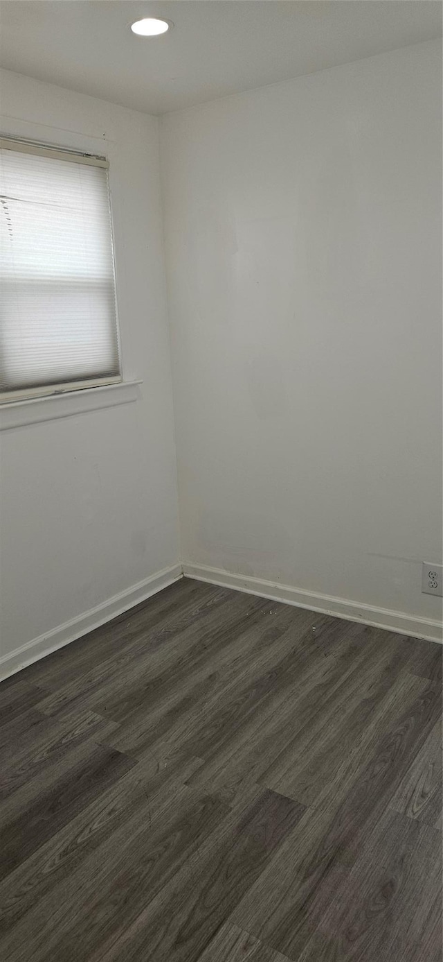 spare room featuring dark wood-style flooring and baseboards