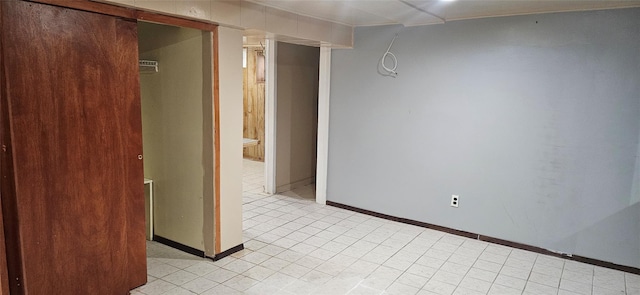 empty room featuring baseboards and light tile patterned floors