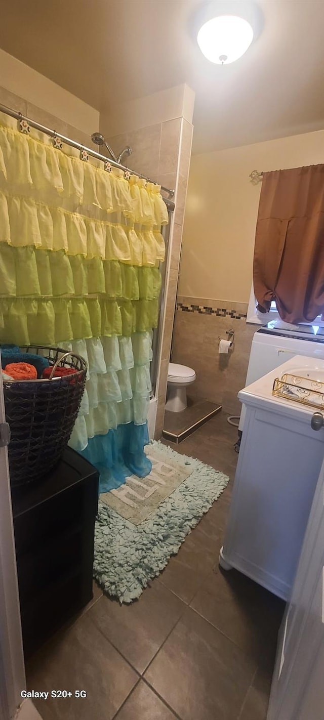 bathroom featuring tile walls, tile patterned flooring, wainscoting, toilet, and a shower with shower curtain