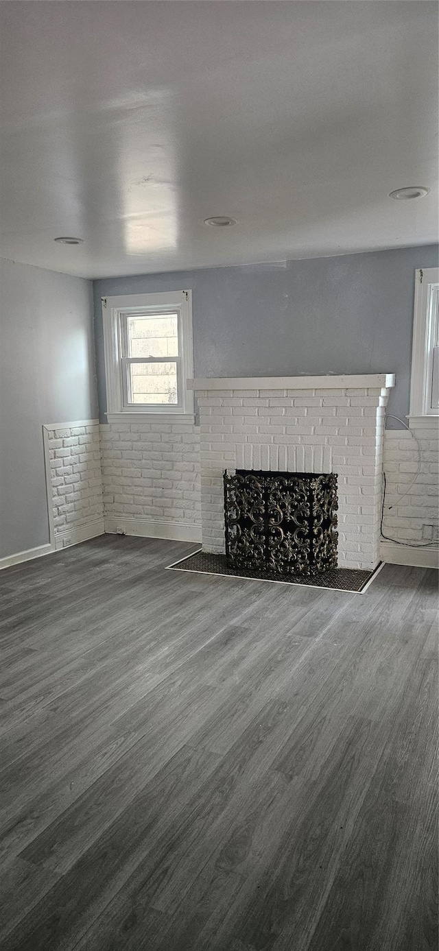 unfurnished living room featuring a brick fireplace and wood finished floors