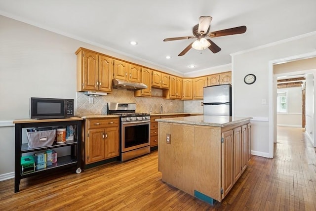 37 Remson St, Valley Stream, NY 11580 - kitchen with appliances with stainless steel finishes, under cabinet range hood, hardwood / wood-style flooring, a center island, and tasteful backsplash