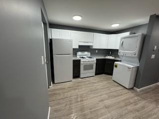 kitchen with light wood finished floors, gas range gas stove, freestanding refrigerator, under cabinet range hood, and stacked washer and clothes dryer