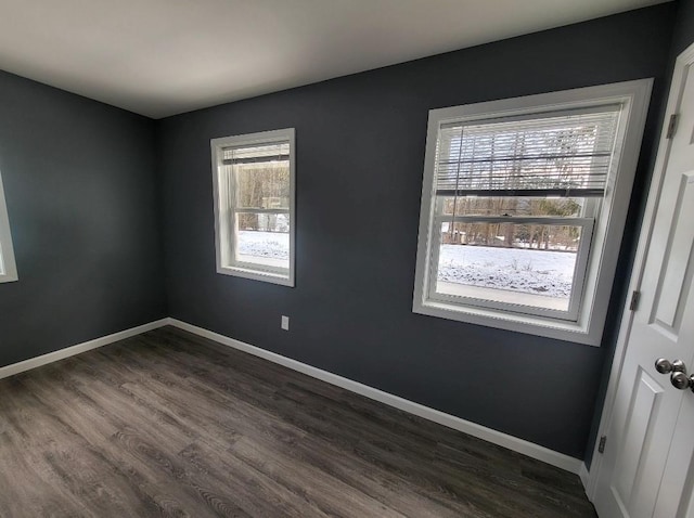 unfurnished room featuring baseboards and dark wood finished floors