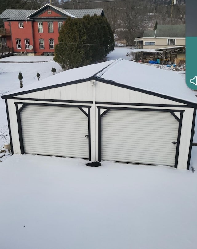 snow covered garage with a detached garage