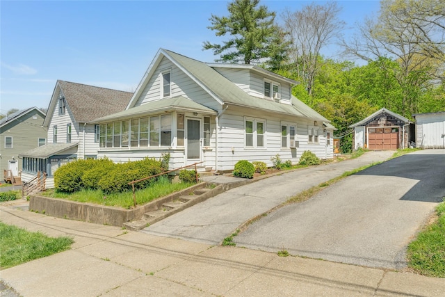 bungalow-style home with driveway, an outbuilding, a sunroom, a garage, and entry steps