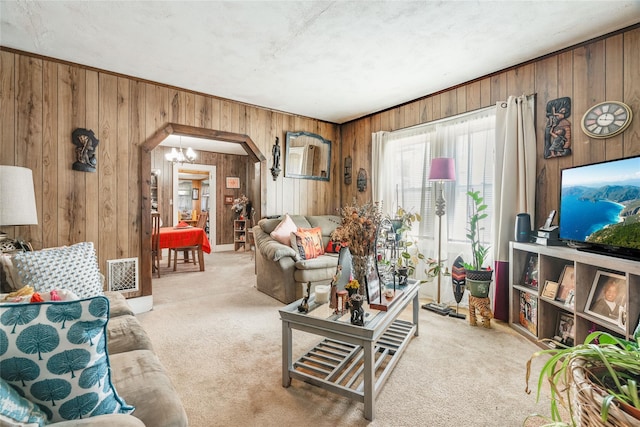 living area featuring wooden walls, arched walkways, visible vents, and carpet