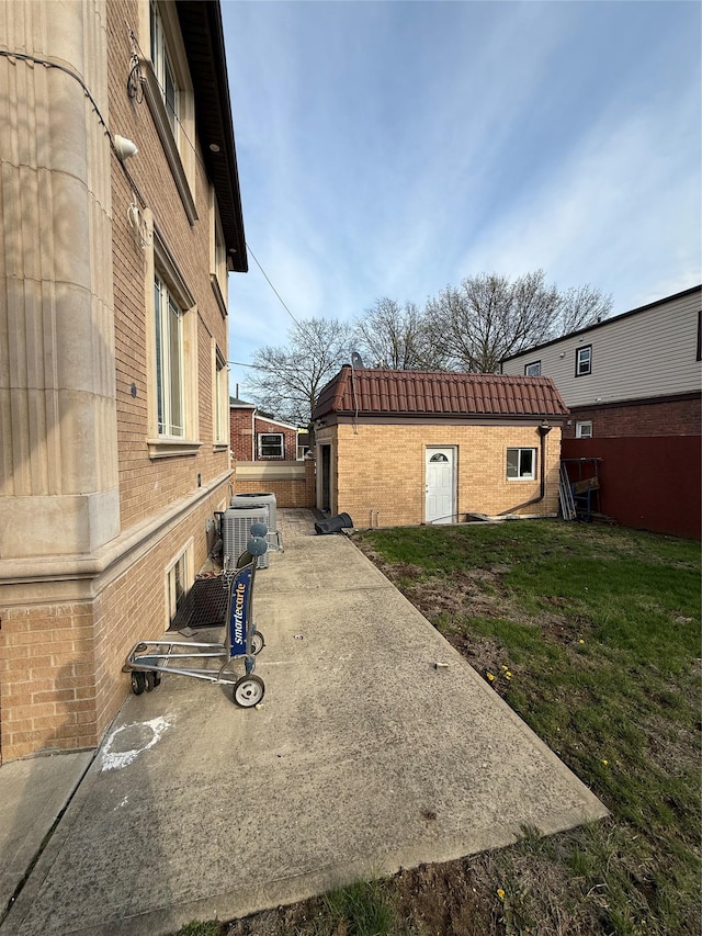 view of side of home featuring brick siding, cooling unit, and a lawn