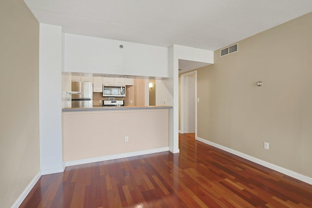unfurnished living room featuring baseboards, visible vents, and wood finished floors