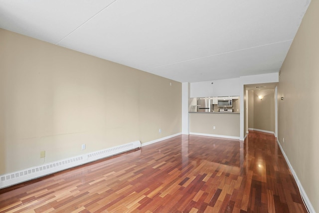 unfurnished room with baseboards, wood finished floors, and a baseboard radiator