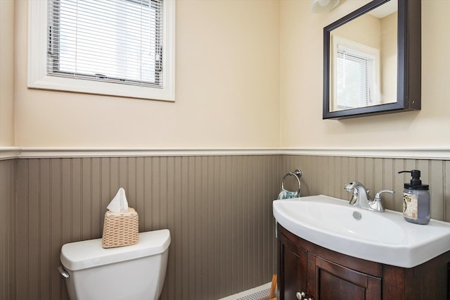 half bathroom featuring toilet, wainscoting, and vanity