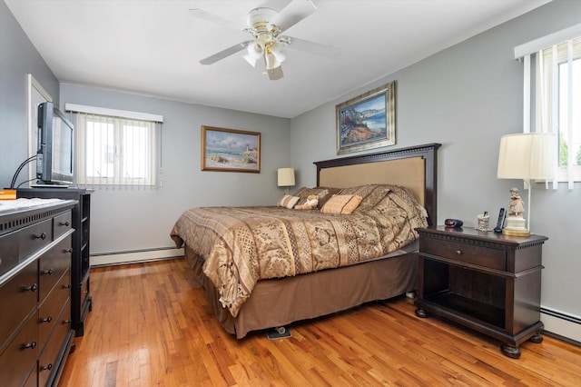 bedroom featuring a ceiling fan, light wood finished floors, and a baseboard heating unit