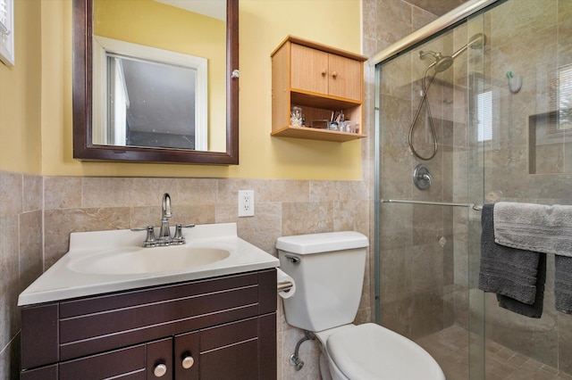 bathroom with vanity, toilet, tile walls, a wainscoted wall, and a stall shower