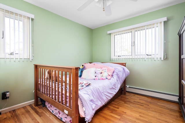 bedroom with baseboards, ceiling fan, baseboard heating, and wood finished floors