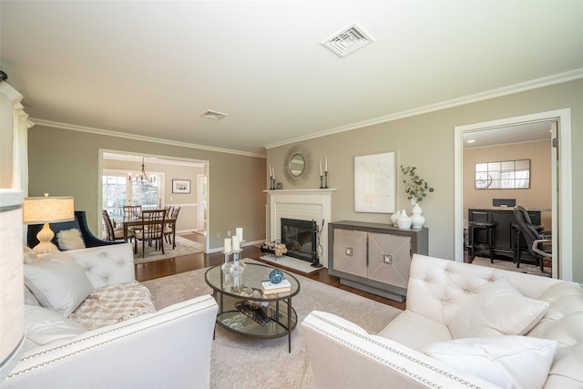 living room with visible vents, crown molding, and a chandelier