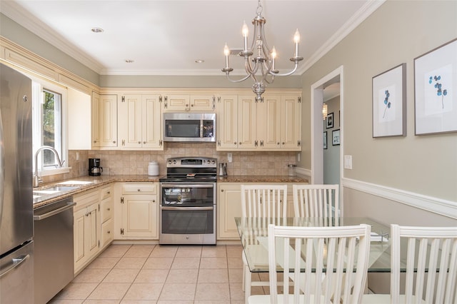 kitchen with an inviting chandelier, cream cabinets, a sink, appliances with stainless steel finishes, and backsplash
