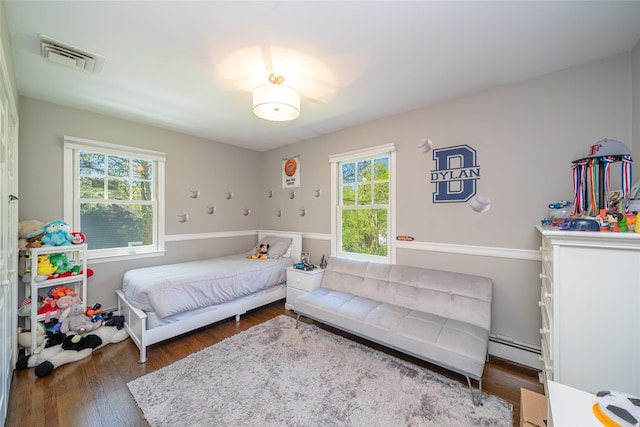 bedroom featuring visible vents, baseboard heating, and wood finished floors