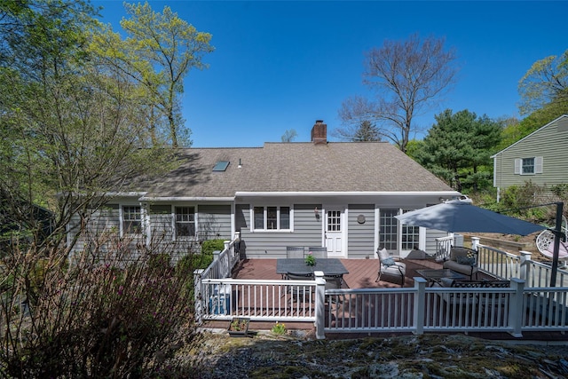 back of house featuring outdoor lounge area, roof with shingles, a chimney, and a deck