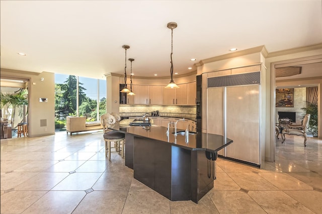 136 The Helm, East Islip, NY 11730 - kitchen featuring paneled built in fridge, dark countertops, backsplash, a kitchen island with sink, and a kitchen bar