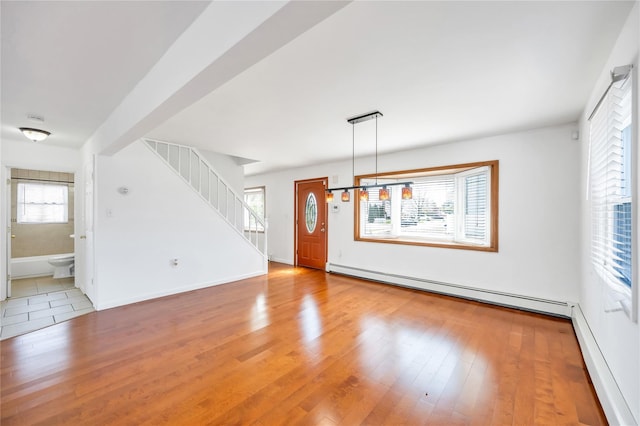 interior space featuring stairway, baseboards, a baseboard heating unit, and wood finished floors