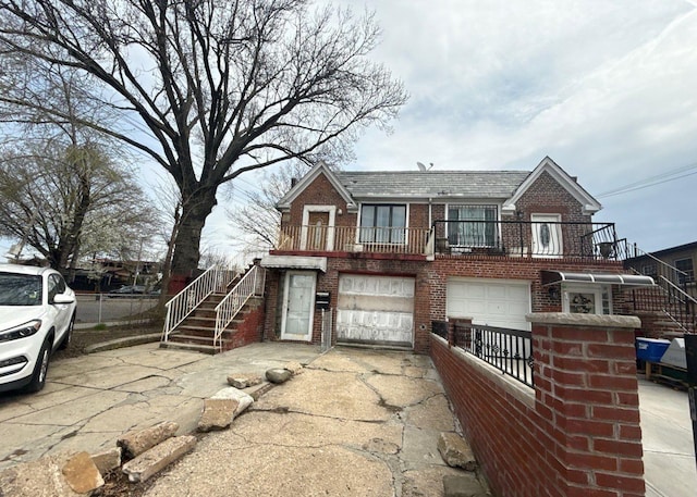 view of front of home featuring stairway, a garage, brick siding, concrete driveway, and fence