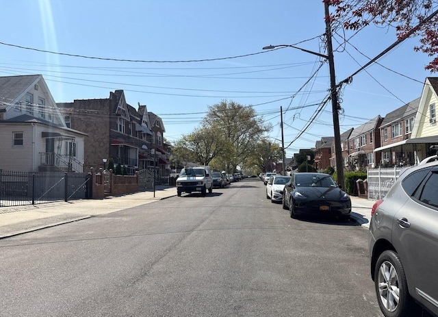 view of road featuring curbs, sidewalks, street lights, and a residential view