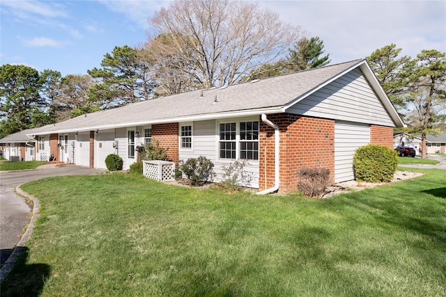 single story home with roof with shingles, a front lawn, brick siding, a garage, and driveway