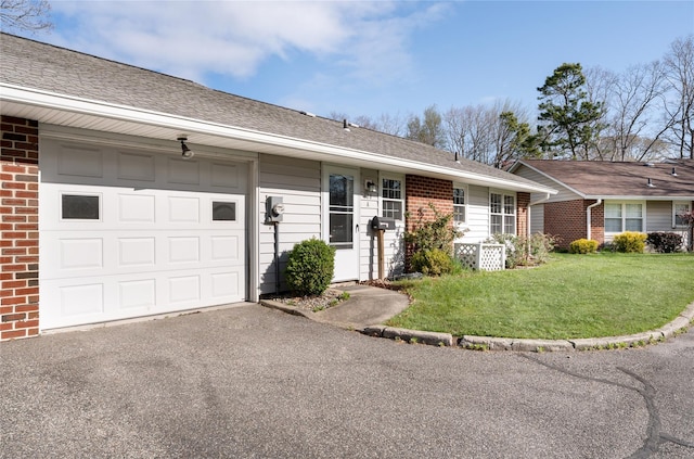 ranch-style home featuring a front yard, a garage, brick siding, aphalt driveway, and a shingled roof