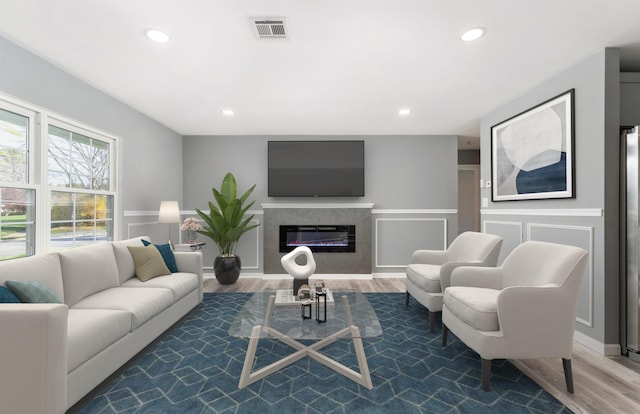 living room with a glass covered fireplace, recessed lighting, wood finished floors, and visible vents