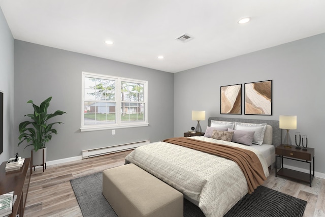 bedroom featuring baseboards, visible vents, baseboard heating, and light wood finished floors