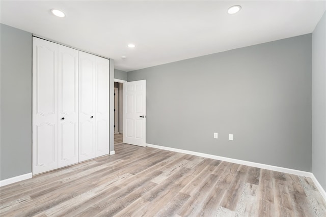 unfurnished bedroom with recessed lighting, baseboards, light wood finished floors, and a closet