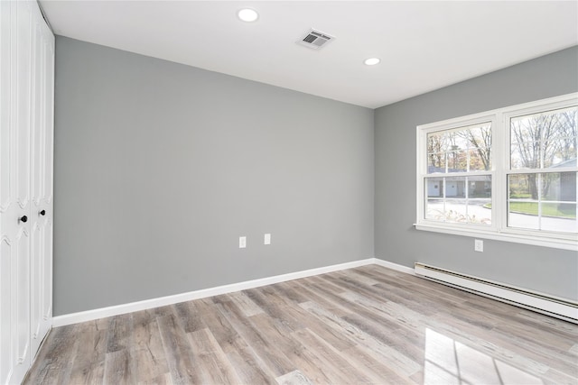 spare room with visible vents, recessed lighting, a baseboard heating unit, and wood finished floors