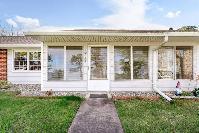 property entrance with a yard and brick siding