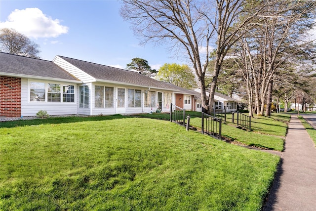 single story home featuring a shingled roof, brick siding, and a front yard