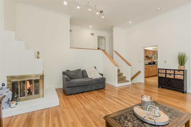 living room with stairway, crown molding, light wood finished floors, and visible vents