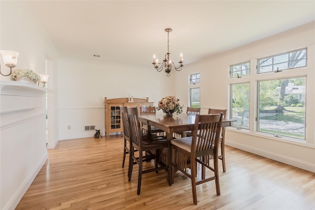 dining room featuring crown molding, visible vents, light wood-style flooring, and a notable chandelier