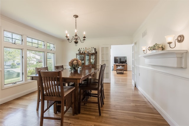 dining space featuring crown molding, baseboards, light wood-style floors, and a chandelier