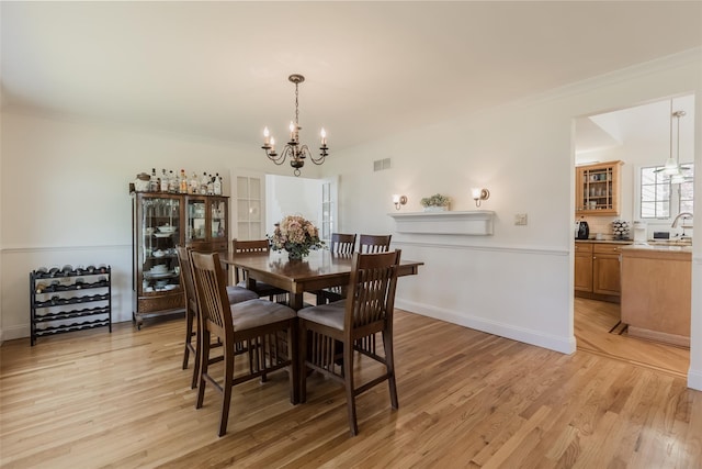 dining room with crown molding, an inviting chandelier, visible vents, and light wood-type flooring